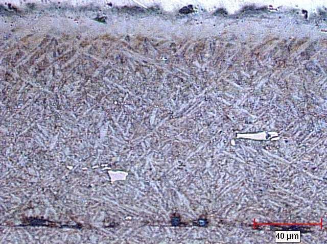 Micrograph showing carbides and a crack developing parallel to the surface